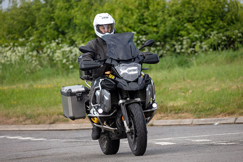 Guy riding BMW GS wearing adventure helmet and panniers